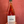 A hand holding a bottle of Ostatu Rosado 2020 rosé wine against a textured red background.
