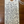 A handwritten cream-colored paper tag with a wooden punch hole and white string, printed with the text 'Ovum "Off the Grid" 100. Riesling Willamette, Oregon Woman Winemaker Ksenija Kostiā House ~ All Nature ~ Intensey aromatic, and luscious textured ~ Liquid gold in glass ~ Long aging potential ~ Apricot tart with lemon + thyme crust ~ Bone dry minerality ~ Aged in Acacia wood ~ Like zip lining for your mouth' on a dark wood background.