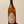 A hand holding a large brown glass wine bottle with a vintage-style oval map label that reads 'NOVUM'.