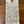A handwritten cream-colored paper tag with a brown circular hole at the top, featuring cursive writing about 'Poggio delle Basciati' wine, placed on a wooden surface.