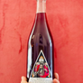 Bottle with a label featuring a person in a red outfit against a red background