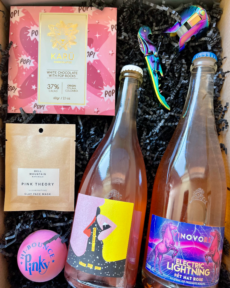 This box includes Vinovore Electric Lightning Rosé, Between Us Pink Pét-nat Rosé, Bell Mountain Pink Theory Clay Mask, Classic Pinky Bouncy Ball, Karü Chocolates 37% White Cocoa with Pop Rocks, Mirage Corkscrew Wine Opener and a champagne stopper - choose one color.