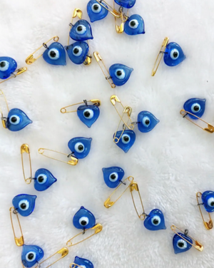 hand blown blue glass evil eye on a gold safety pin