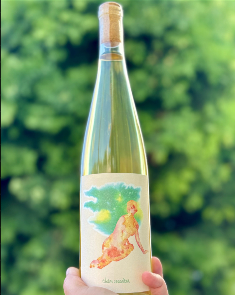 Wine bottle with a colorful label held against a blurred green background