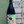 Bottle of wine with a colorful label held against a textured wall.