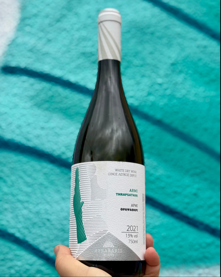 Wine bottle held by a hand with a blue textured background