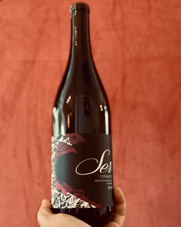 Wine bottle with a decorative label held against a red background
