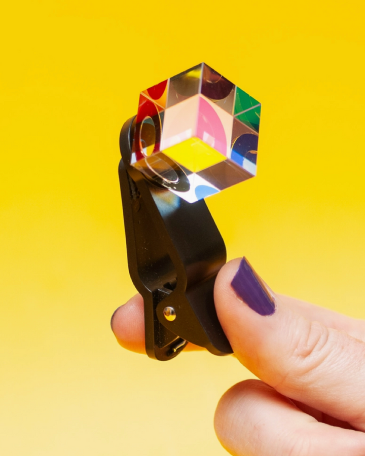 Crystal prism held by a hand against a yellow background