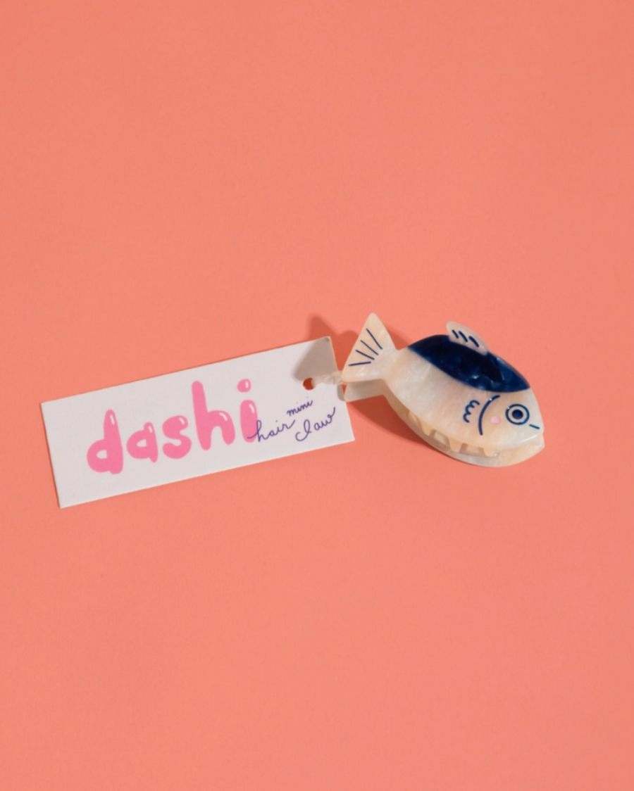 Fish-shaped hair clip with 'dashi' label on a pink background