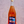 a hand holding a pink wine bottle with label that has a racecar on it against a blurry background