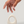 Hand reaching towards a white ceramic object on a light gray background
