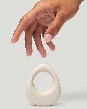 Hand reaching towards a white ceramic object on a light gray background