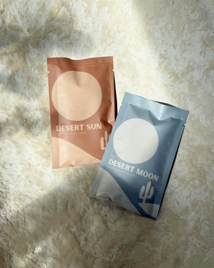 Two skincare product packages labeled 'Desert Sun' and 'Desert Moon' on a textured surface.