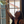 Person pouring a drink from a bottle into a glass with a window in the background