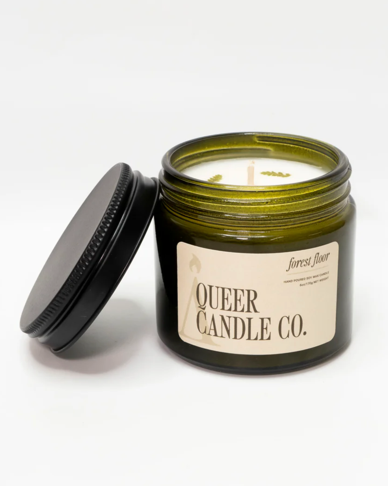 Green candle jar with lid and 'Queer Candle Co.' label on a white background