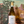 Bottle of Zena wine held in front of a painted landscape with trees and a deer.