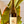 A hand holds a bottle of Zouzou wine against a background of large green tropical leaves and white window blinds.