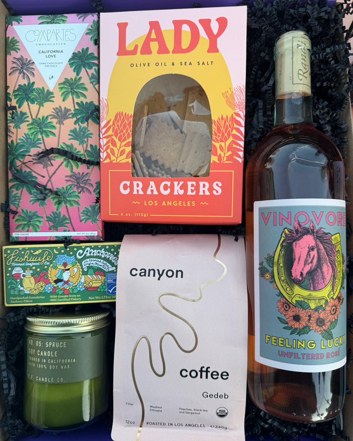 Our Local Love - Feeling Lucky Box includes:

Compartés California Love Dark Chocolate Salted Pretzel Bar, Fishwife Anchovies in Spanish EVOO, P.F. Spruce Jar Candle, Gedeb Canyon Coffee, Lady Larder Lady Crackers and Vinovore Feeling Lucky Unfiltered Rosé.