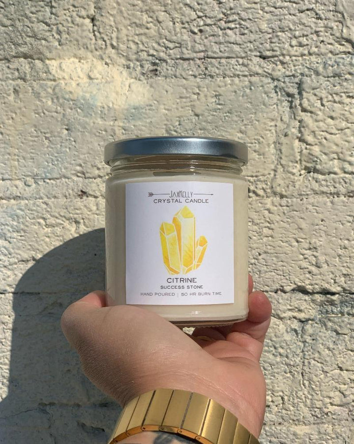 Hidden inside is a Citrine Quartz that radiates vibes of positivity and success. Once your candle has burned retrieve your crystal and carry it with you, or place it in a special space to manifest success in all areas of life Hand-poured and made with 100% American farmed soy wax, the natural essential + fragrance oil blend features notes of tangy Grapefruit and sweet Mangosteen. • 9 oz Jar • 50 HR Burn Time