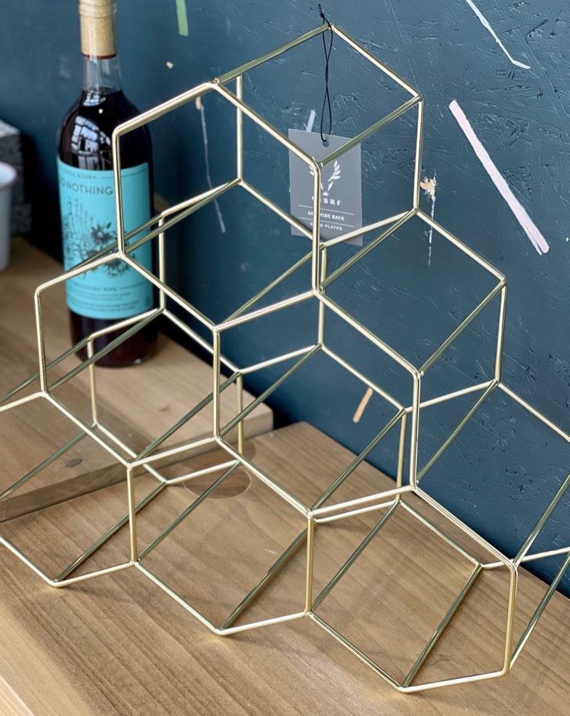 An excellent selection of wine deserves to be displayed in style. Gold-plated stainless steel is wrapped and welded to form this stunning six bottle wine rack, perfectly suited for tabletops, countertops and that meticulously curated bottle collection. Gold plated stainless steel construction. Holds six standard wine bottles. Hexagon design.