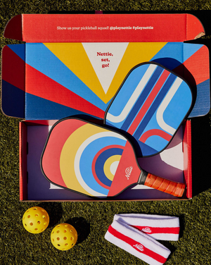 The Nettie Set Double Pack: Perfect for a pickleball tete a tete.  With the Double Pack you get: * 2 pickleball paddles (pattern may vary. Image is for example only). * 2 pickleballs. Because sometimes one ball rolls away. * 2 sweatbands. You’re gonna look great. 